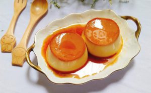 Có 2 bánh flan trên dĩa và 2 cái muỗng kế bên