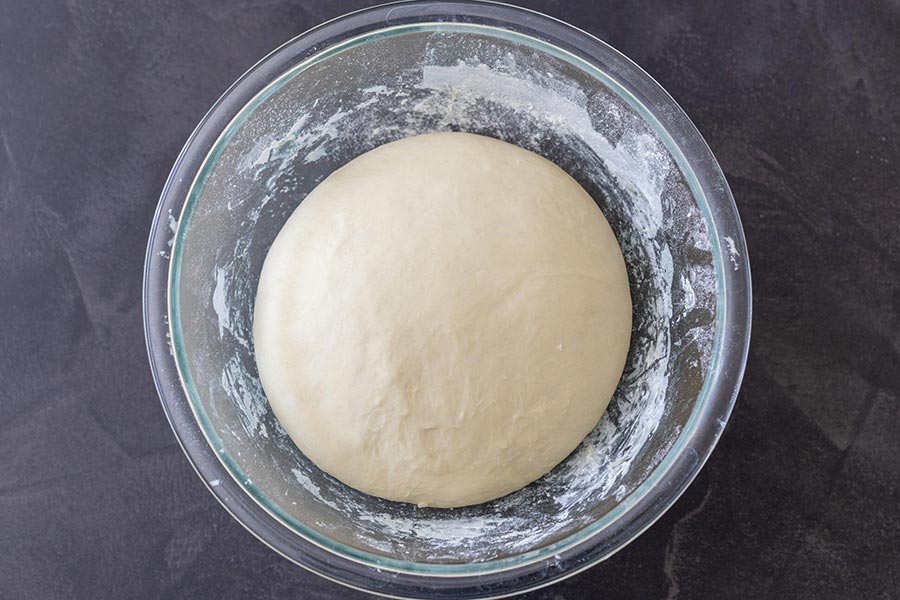 Rây từ từ bột mì vào hỗn hợp bơ sữa, vừa cho bột vào vừa khuấy. Dùng tay nhào hỗn hợp cho đến khi bột không còn dính tay là được.