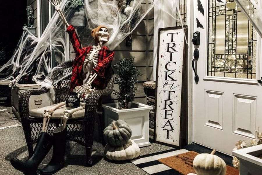 Mẫu trang trí cửa quán cà phê halloween với bộ xương và bí ngô.