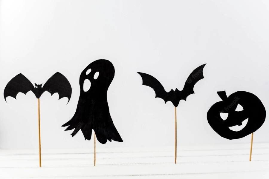 Trang trí Halloween với cây cắm hình dơi, bí ngô, bóng ma màu đen.