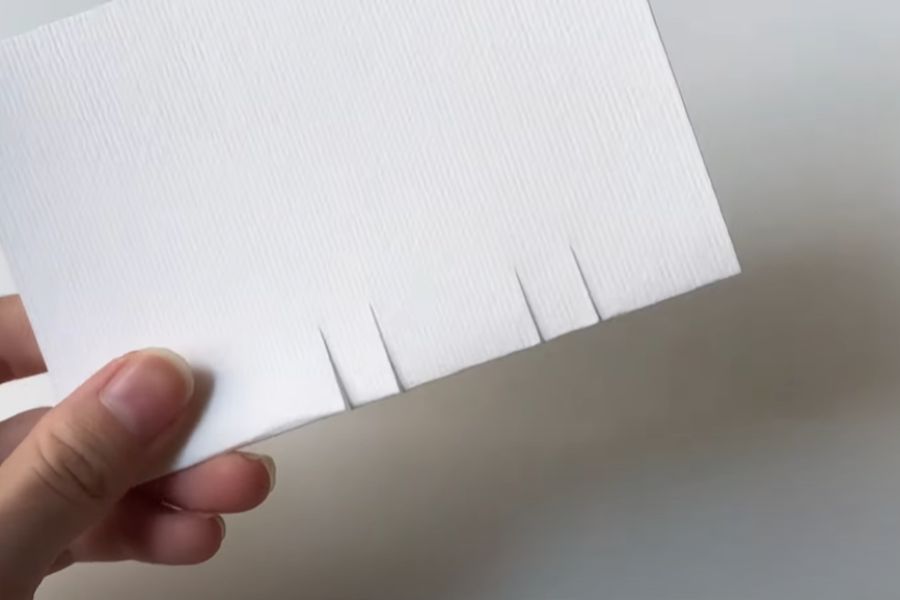 Dùng kéo cắt 4 lần phần nếp gấp của giấy.