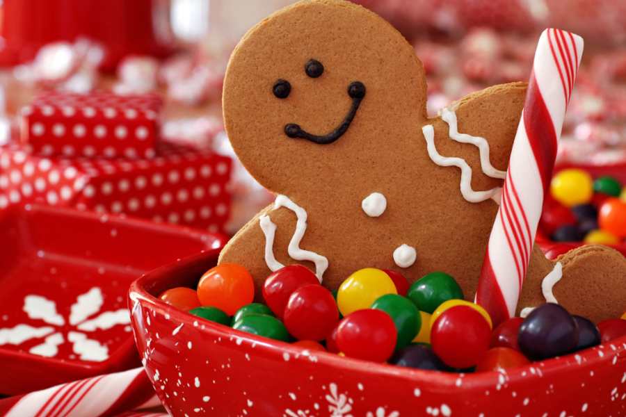 Bánh và kẹo có họa tiết Giáng Sinh trang trí cho văn phòng được đặt trong những chiếc đĩa màu đỏ nổi bật.