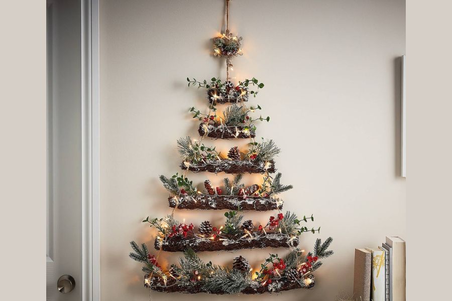 Trang trí cây thông Noel treo tường bằng nhánh cây cùng phụ kiện Noel và lá cây thông.
