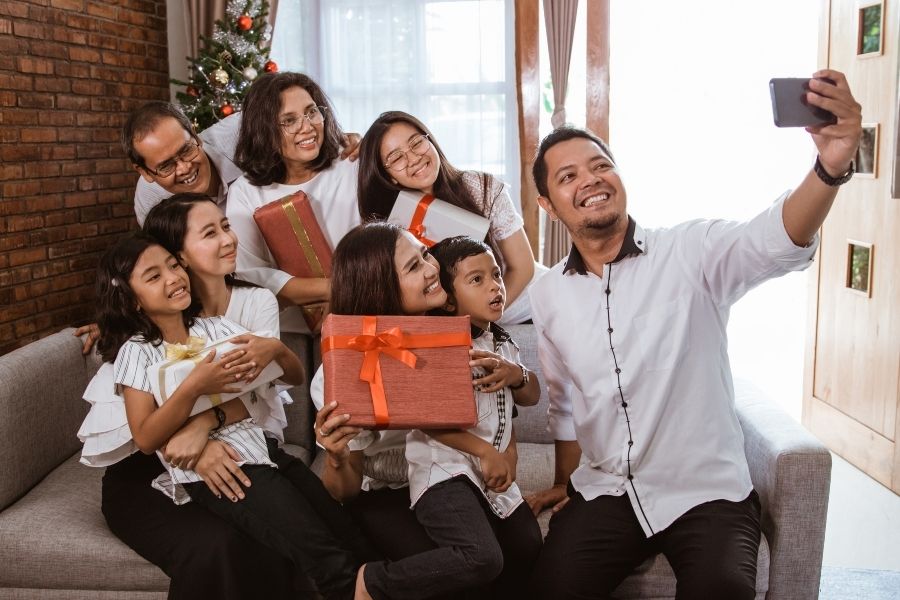 Chụp ảnh Noel gia đình cùng hộp quà màu đỏ.