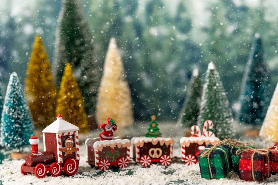 Mô hình đoàn tàu lửa họa tiết Noel đang đi trong khung cảnh tuyết rơi tại rừng thông.