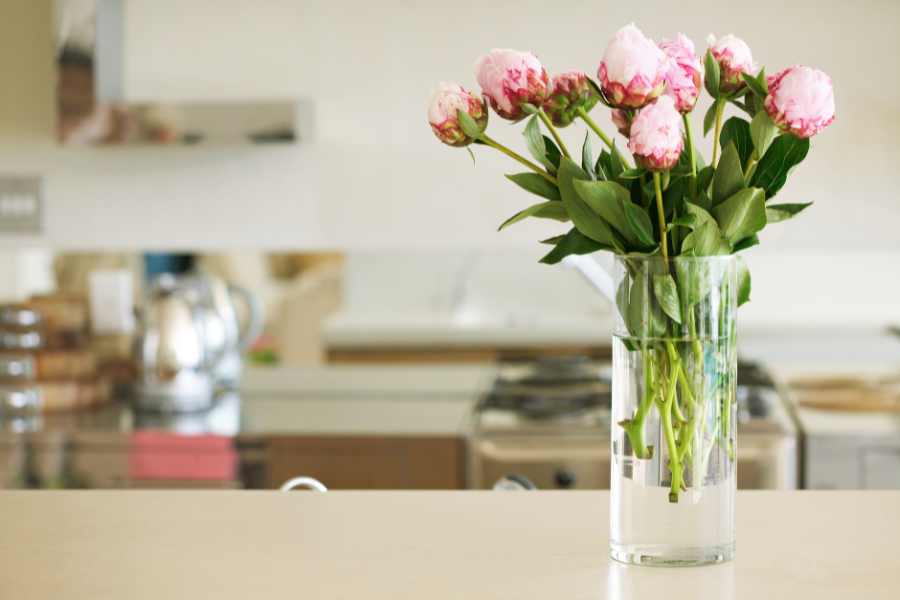 Cắm hoa để bàn bằng bình thủy tinh để cho không gian bếp.