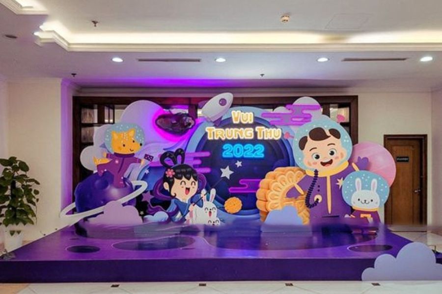 Sân khấu mầm non với phông nền đêm trăng rằm, có hình chú Cuội, chị Hằng và tông màu tím chủ đạo.