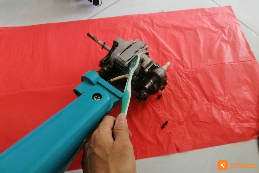 Dùng bàn chải lau bụi bẩn bám lên trục.