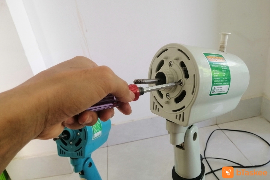 Dùng tua vít để tháo ốc trục quay.